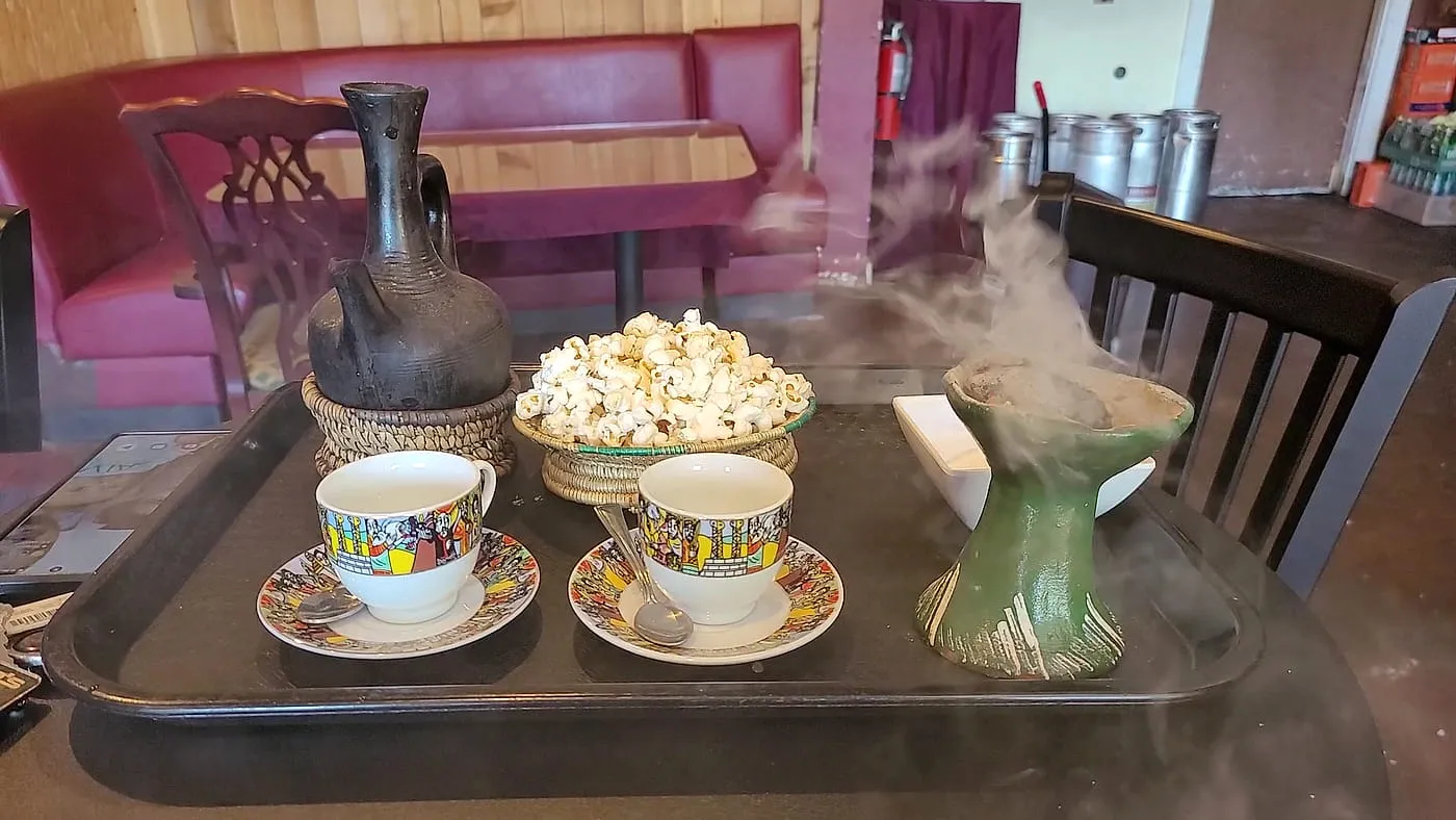 Coffee tray at Zagol with a jebena, two cups and a woven bowl of popcorn