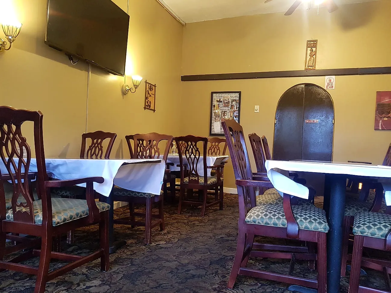 Dining room at Zagol with white linen, high-backed wooden chairs and Ethiopian artwork on ochre walls