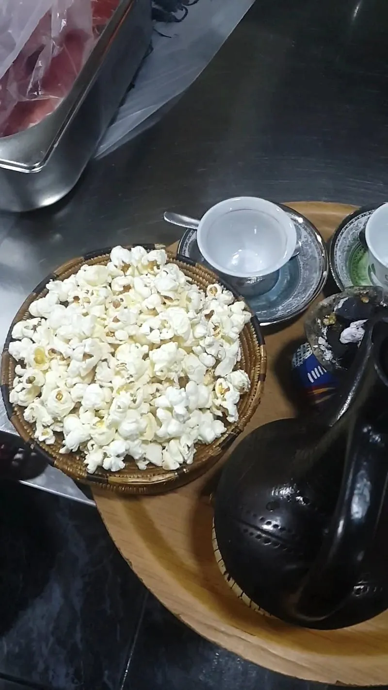 Woven basket of freshly popped corn next to a jebena coffee pot at Zagol