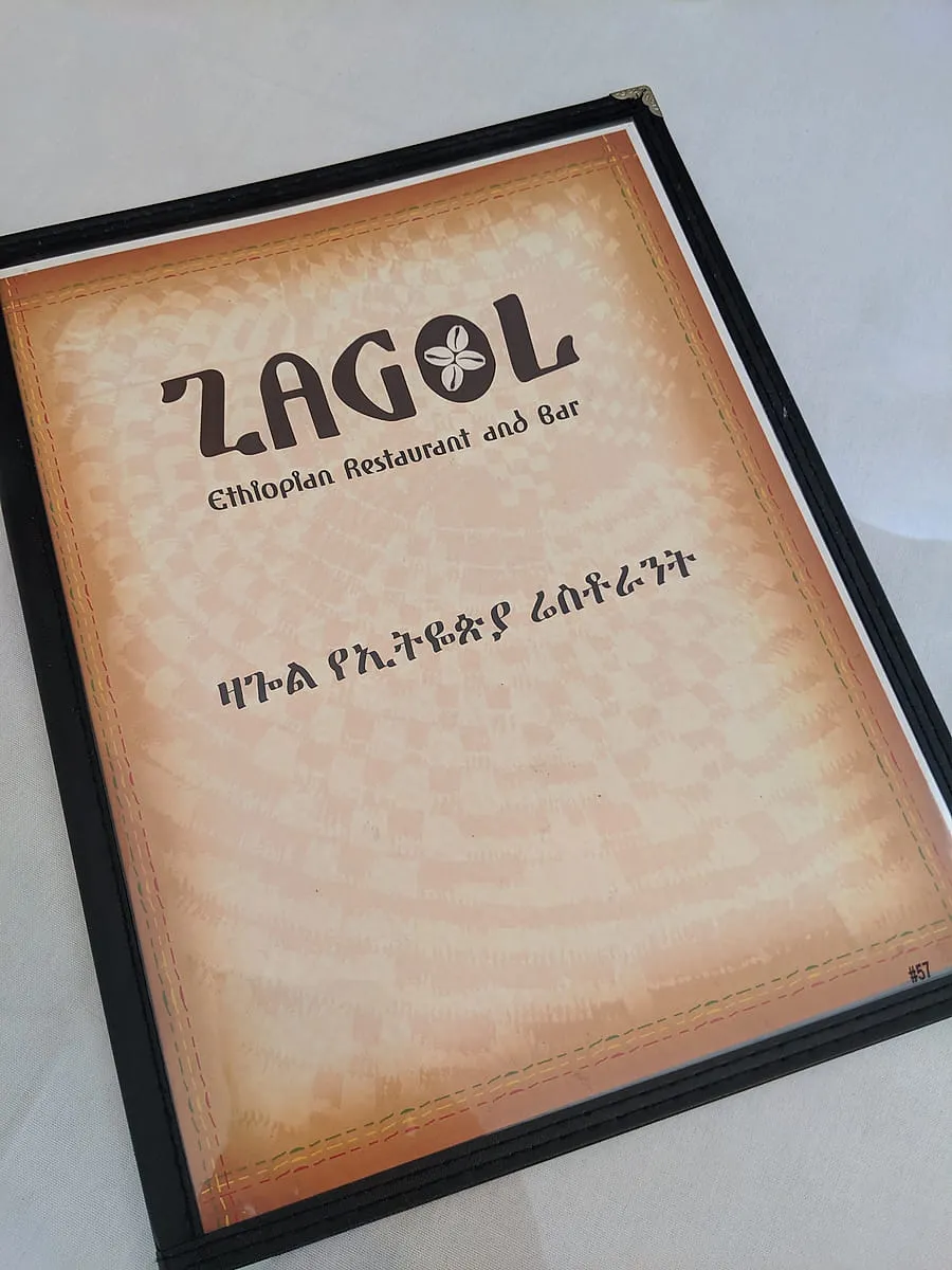 Zagol menu cover, with the restaurant name over a woven basket pattern and the name in Amharic